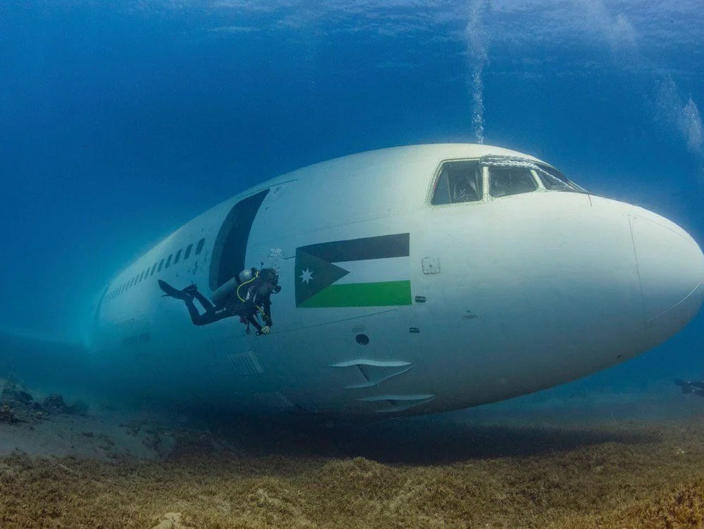 A diver beside the nose of the sunken Tristar airplane wreck off Aqaba, with the Jordanian flag painted on its fuselage